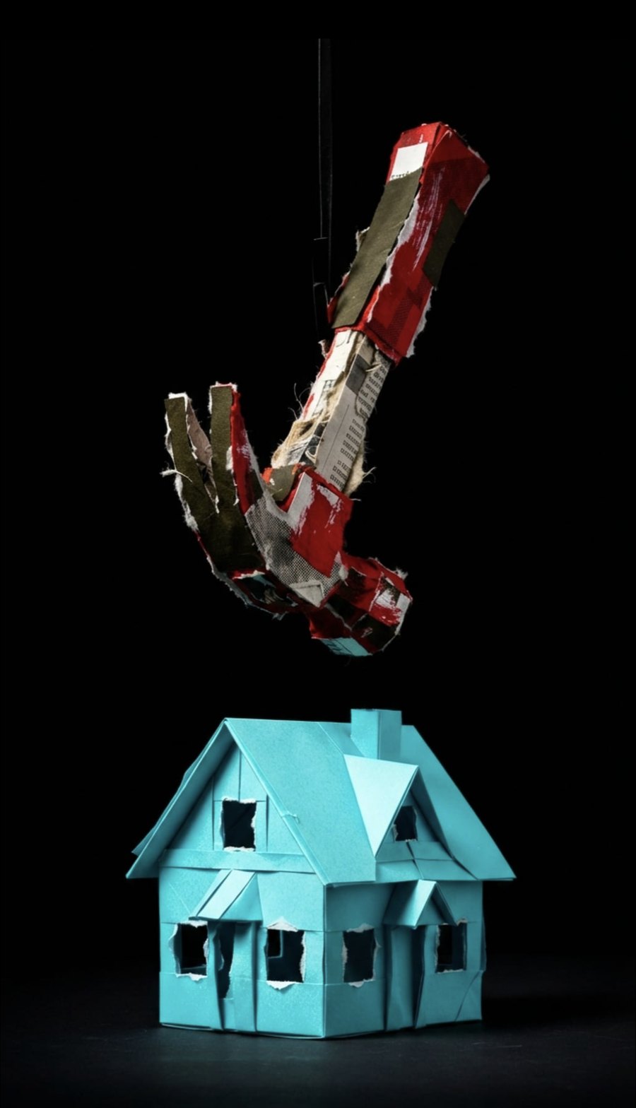Paper sculpture: a hammer suspended above a small house